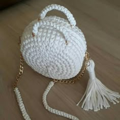 a white crocheted purse with tassels on the handle and chain around it