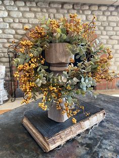 a vase filled with yellow flowers sitting on top of a table next to an old book