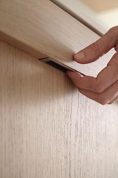 a hand holding a piece of paper near a wooden door handle on a wood paneled wall