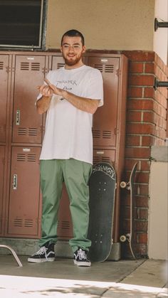 a man standing in front of lockers holding a skateboard