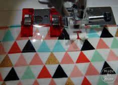 the sewing machine is on top of the colorful fabric and has two red buttons in front of it