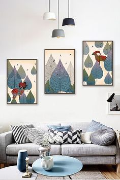 three paintings hang on the wall above a couch in a living room with blue accents