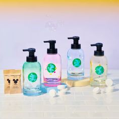 soaps and lotion bottles are lined up on a counter with bubbles in the air