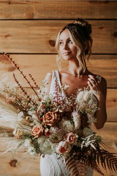 a woman holding a bouquet of flowers in front of a wooden wall