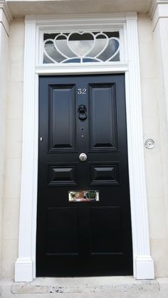 a black front door with two hearts on the top and bottom panel, flanked by white trim