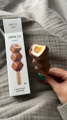 a person is holding an egg and chocolate popsicle in their hand next to the box