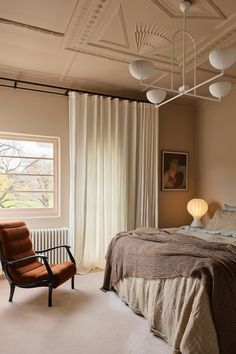 a bedroom with a bed, chair and window