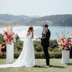 a bride and groom standing in front of their wedding ceremony setup with flowers on the ground