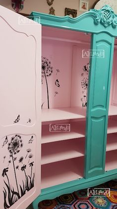 a pink and blue armoire with dandelions painted on the side, in front of a mirror