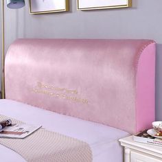 a pink bed headboard with writing on the side and two pictures hanging above it