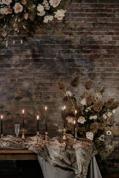 a table topped with candles and flowers next to a brick wall