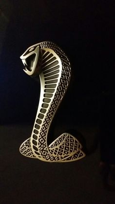 an intricately carved cobra head on a black background with the light coming from behind it