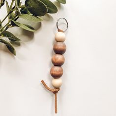 a wooden beaded keychain hanging from a tree branch next to a potted plant