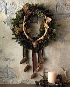 a deer's head hanging on the wall next to a candle and some pine cones