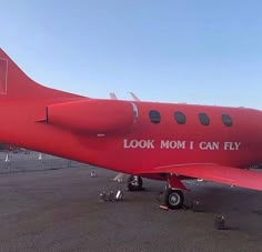 a red plane with the words look mom i can fly painted on it's side