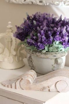 some purple flowers are in a white vase on a table next to an old book