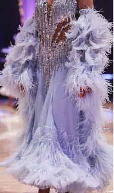 a woman in a dress with feathers on the runway