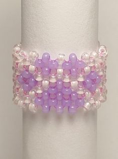 a purple and white beaded bracelet on top of a roll of toilet paper