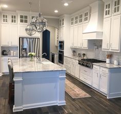 a kitchen with white cabinets and an island in the middle of the room that has a chandelier hanging from it's ceiling