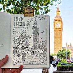 a hand holding an open book in front of the big ben clock tower