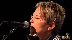 a woman with glasses singing into a microphone