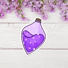 a purple flask sticker sitting on top of a wooden table next to flowers