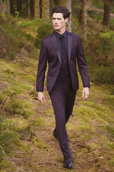 a man in a suit walking through the woods