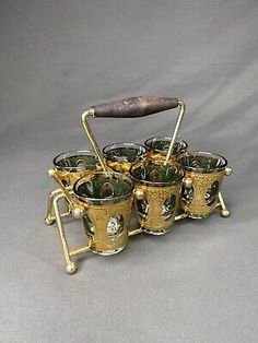 an antique brass tea set with six cups and a wooden handle