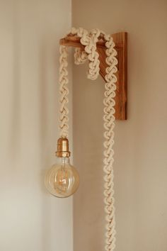 a light that is on the wall next to a roped up lamp shade holder