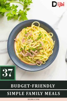 a blue bowl filled with spaghetti and meat on top of a white table next to parsley