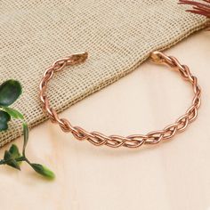 a close up of a bracelet on a table next to a plant and a cloth