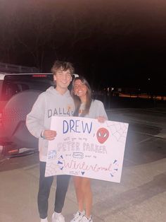 two people standing next to each other holding a sign