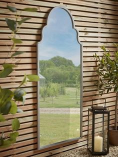 a large mirror sitting on top of a wooden wall next to a potted plant