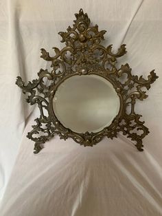 a mirror that is on top of a white sheet with an ornate design in the middle