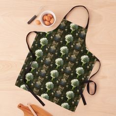 an apron with a pattern of white flowers on it and eggs in a bowl next to it