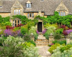 a house with many flowers and plants around it