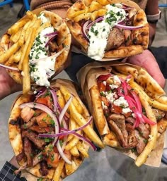 three pita sandwiches with meat, onions and cheese on them are being held by someone's hands