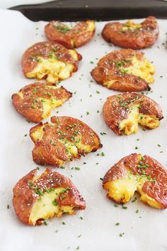 small pizzas with cheese and chives are on a baking sheet, ready to be eaten