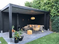 an outdoor living area with couches and tables in the grass, surrounded by greenery