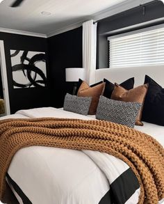 a white bed topped with lots of pillows next to a black and white painting on the wall