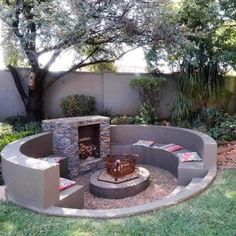 an outdoor fire pit surrounded by grass and trees