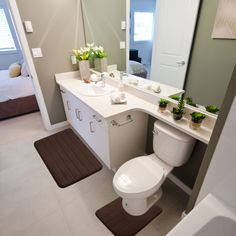 a white toilet sitting under a bathroom mirror next to a sink and bathtub in a room