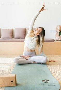 a woman is doing yoga on the floor with her arms in the air while stretching