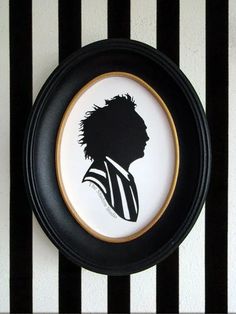 a black and white striped wall with a framed silhouette of a man