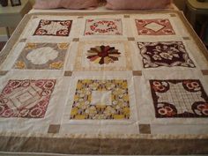 a bed topped with lots of different quilts on it's sides and pillows