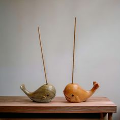 two small wooden whale sculptures sitting on top of a wooden table next to each other