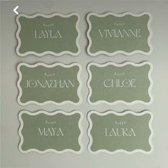 four place cards with names on them in white and green colors are placed next to each other