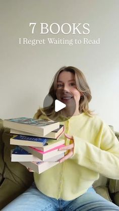 a woman sitting on a couch holding a stack of books