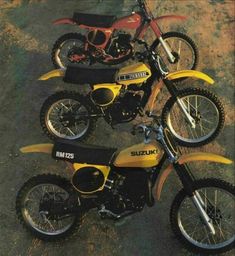 three yellow dirt bikes parked next to each other