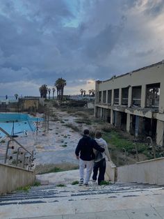 two people are walking up some stairs towards an abandoned swimming pool